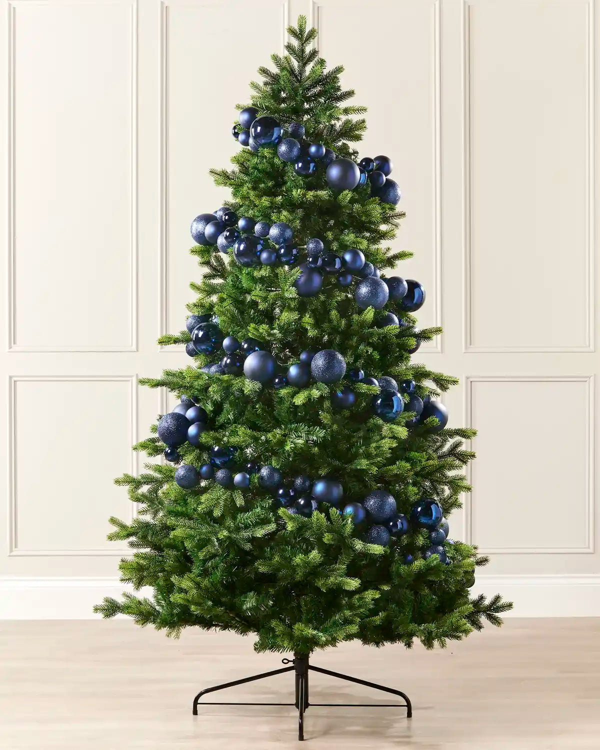 Navy blue bauble garland wrapped around a green Christmas tree with mixed shiny, matt and glitter baubles.