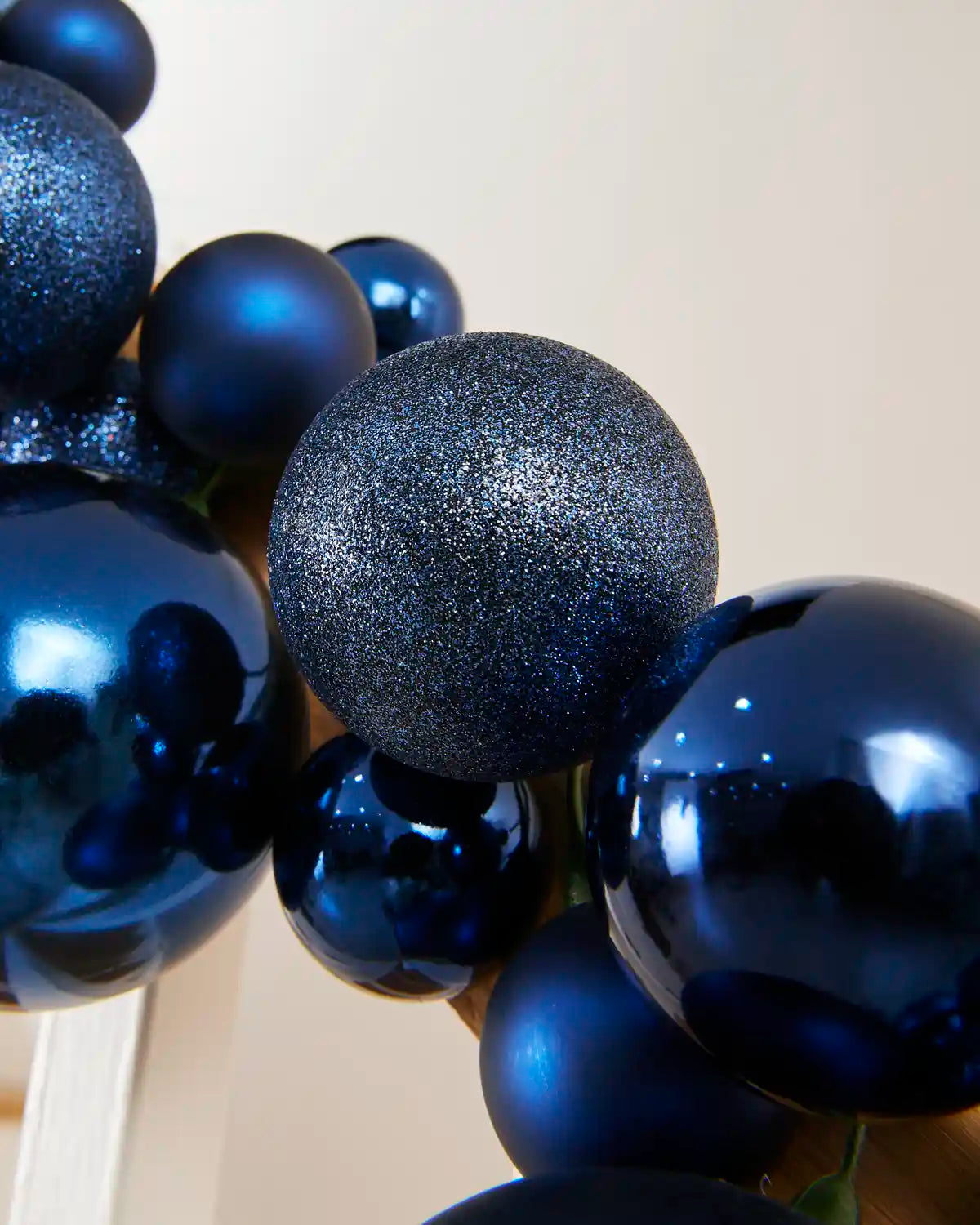Detailed close-up of glitter, shiny and matt navy blue baubles within the garland.