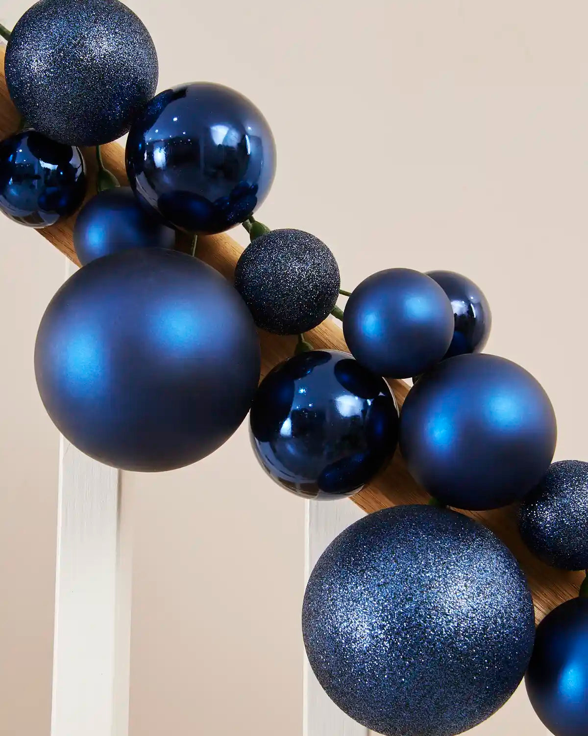Close-up of navy blue baubles in shiny, matt and glitter finishes arranged along a staircase.