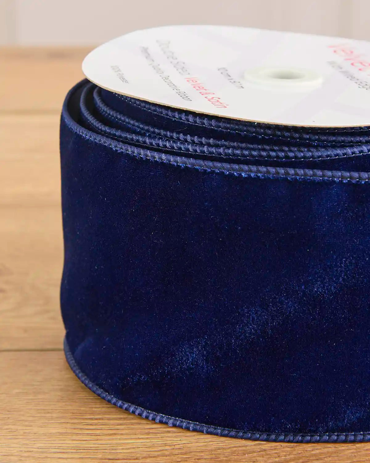 Close-up of the navy velvet surface and wired satin edging on the 10 cm ribbon.