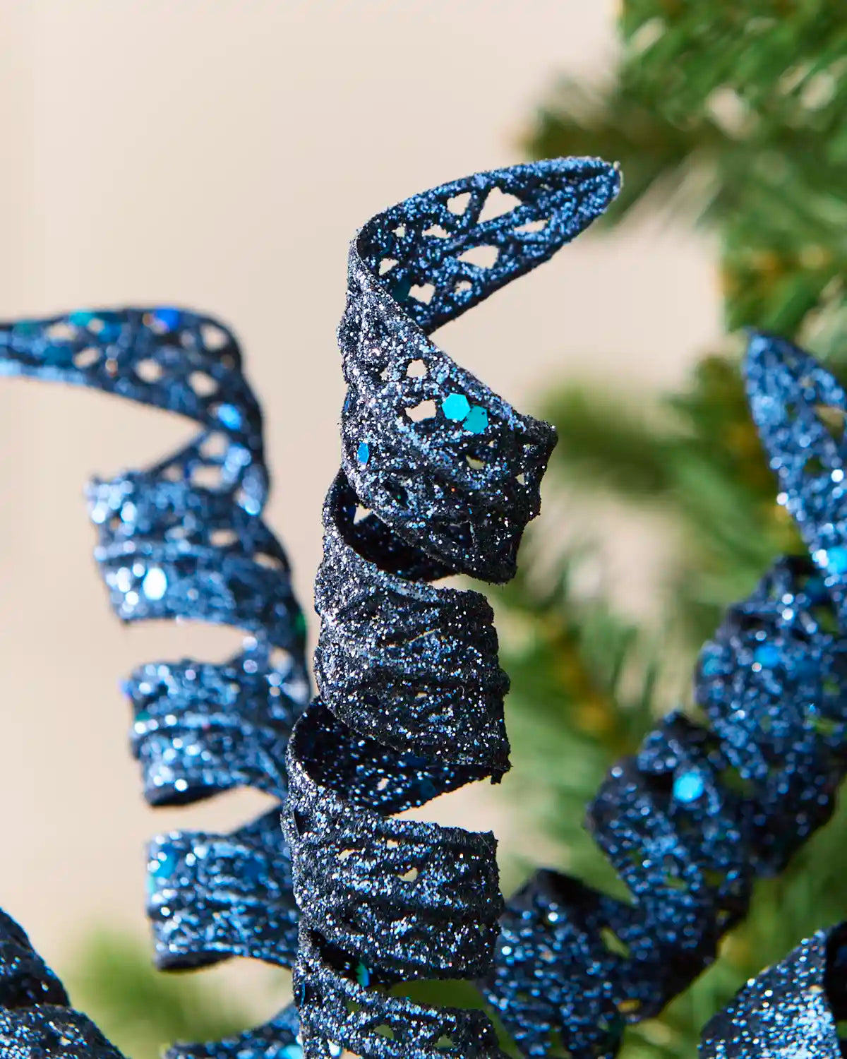 Detailed view of a navy glitter spiral pick showing its curled shape and textured reflective finish.