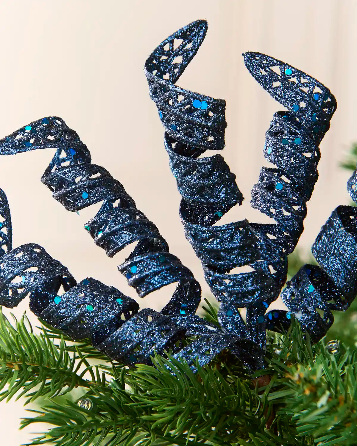 Close-up of navy glitter spiral picks showing curled openwork shapes and reflective sequin details.