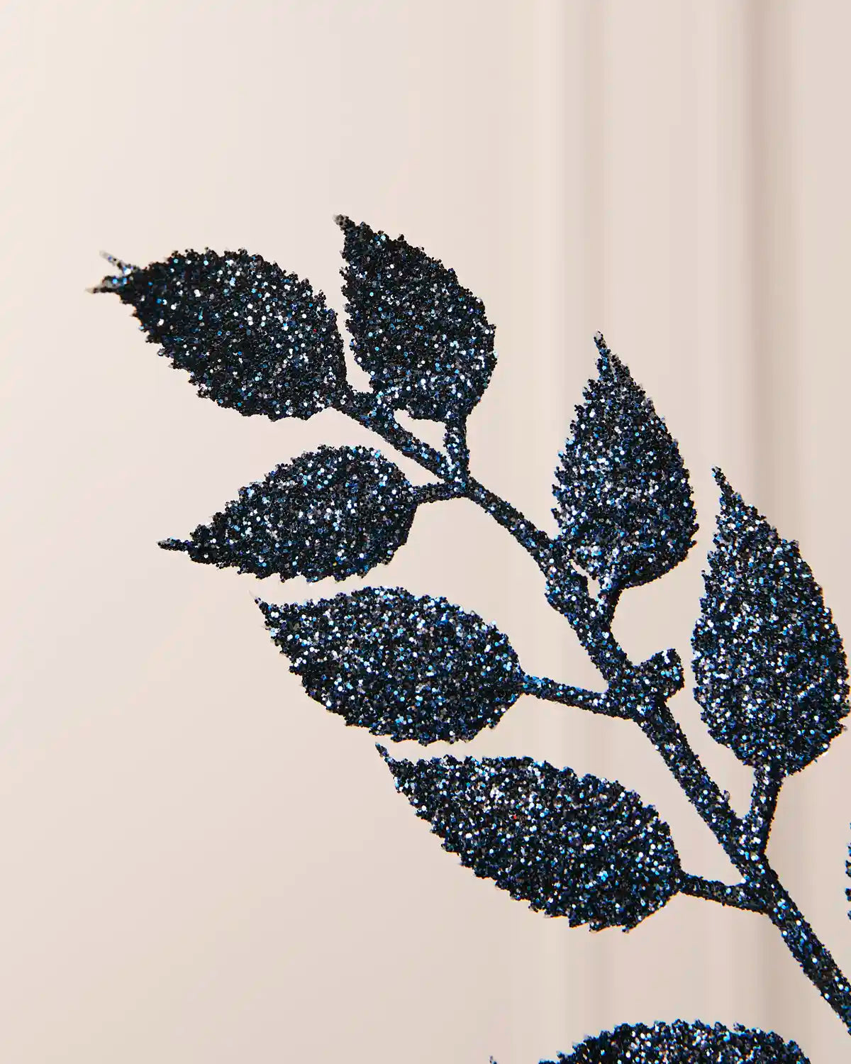 Detailed close-up of the sparkling navy leaves on the 73 cm Christmas tree spray.