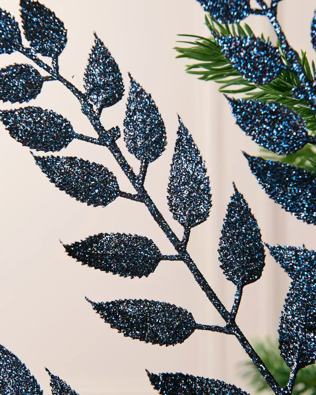 Close-up of the glitter-coated navy leaves on the Christmas tree spray.