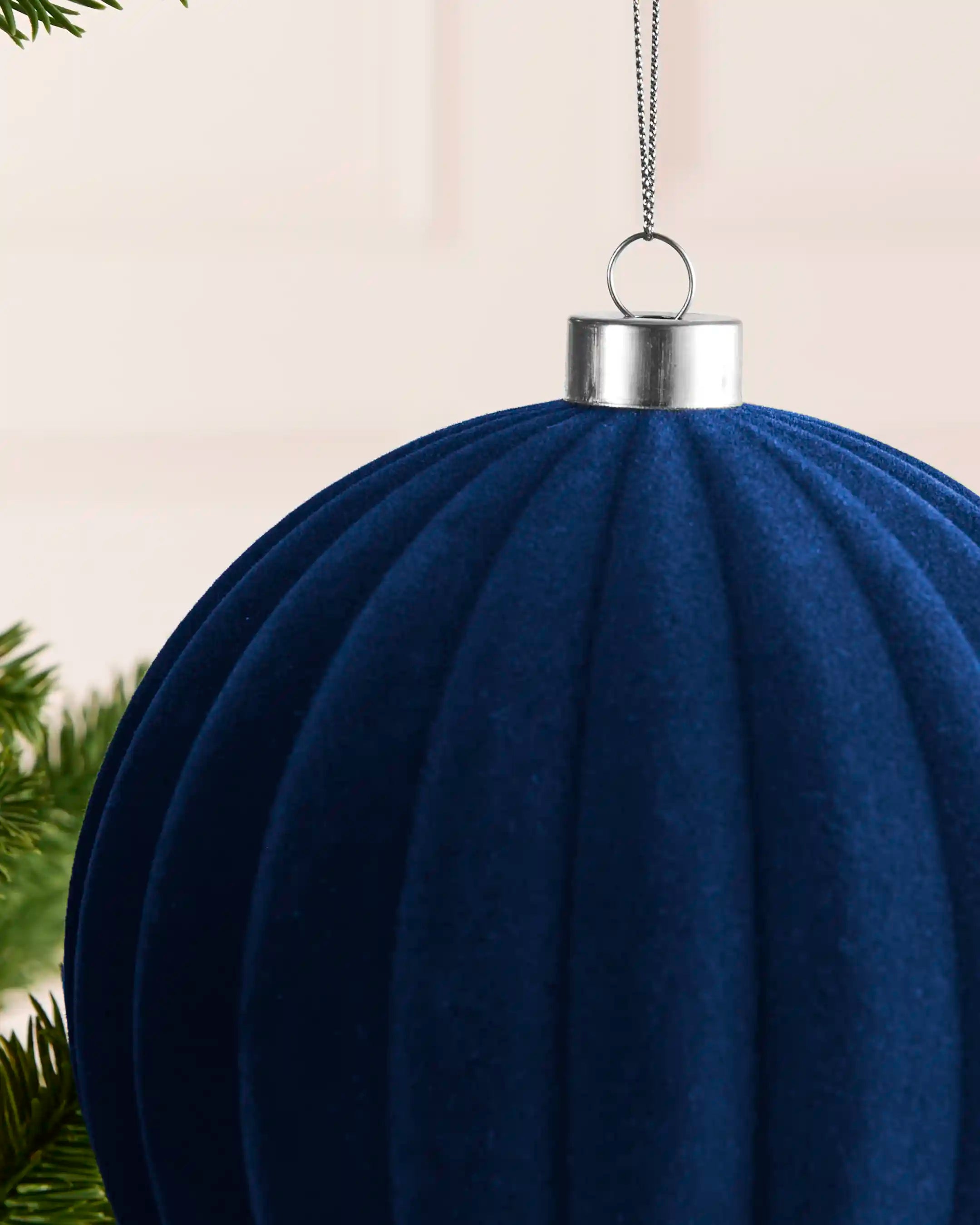 Close-up of the navy velvet ribbed finish, silver metal cap and hanging string on the 15 cm bauble.