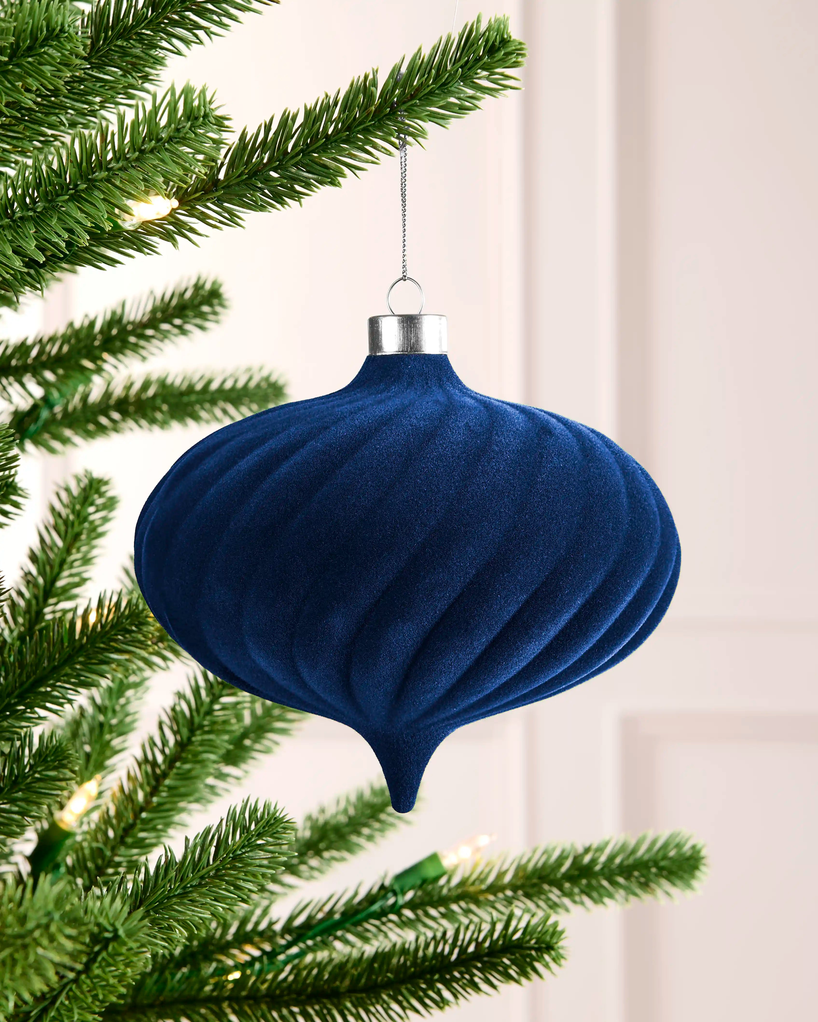 Navy 15 cm oversized velvet bauble with raised spiral detailing, silver cap and hanging string on a Christmas tree.