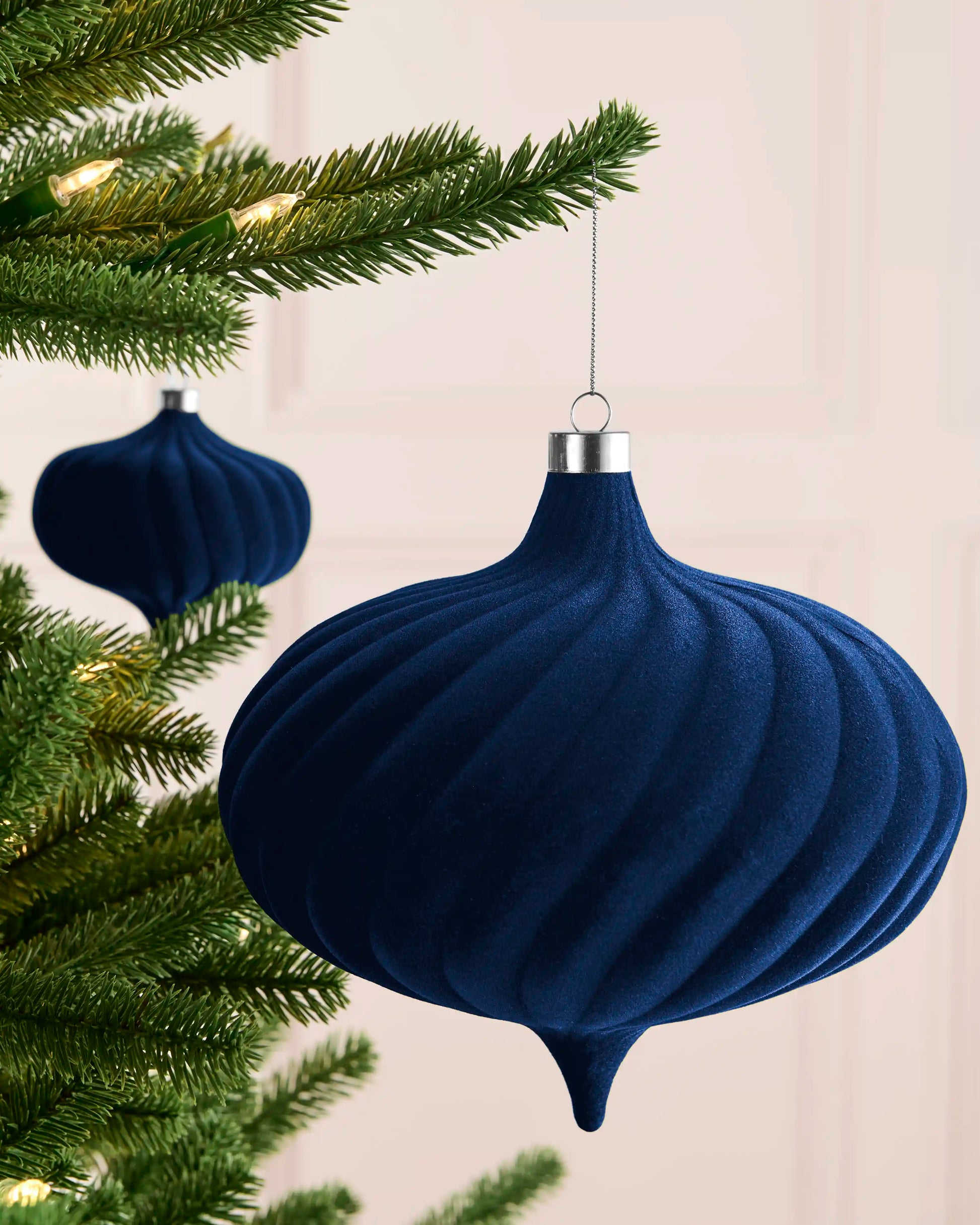 Navy 20 cm spiral velvet bauble hanging from a Christmas tree, showing its curved profile and pointed base.