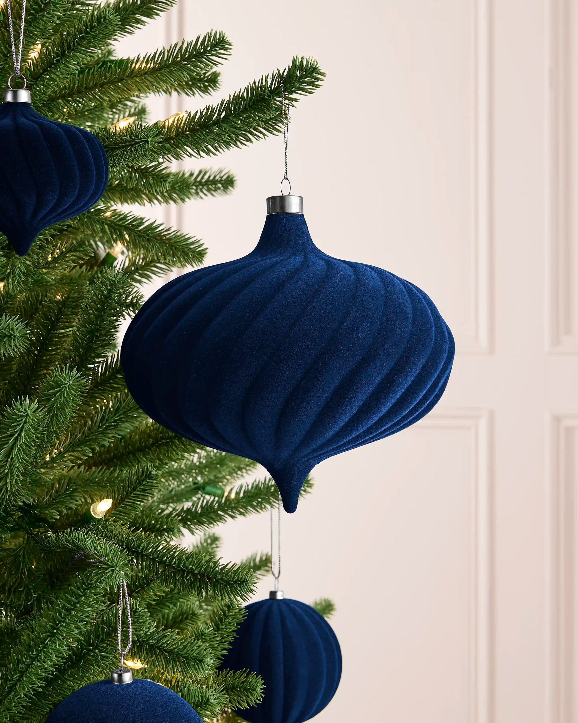 Navy 20 cm oversized spiral velvet bauble displayed among coordinating navy decorations on a Christmas tree.