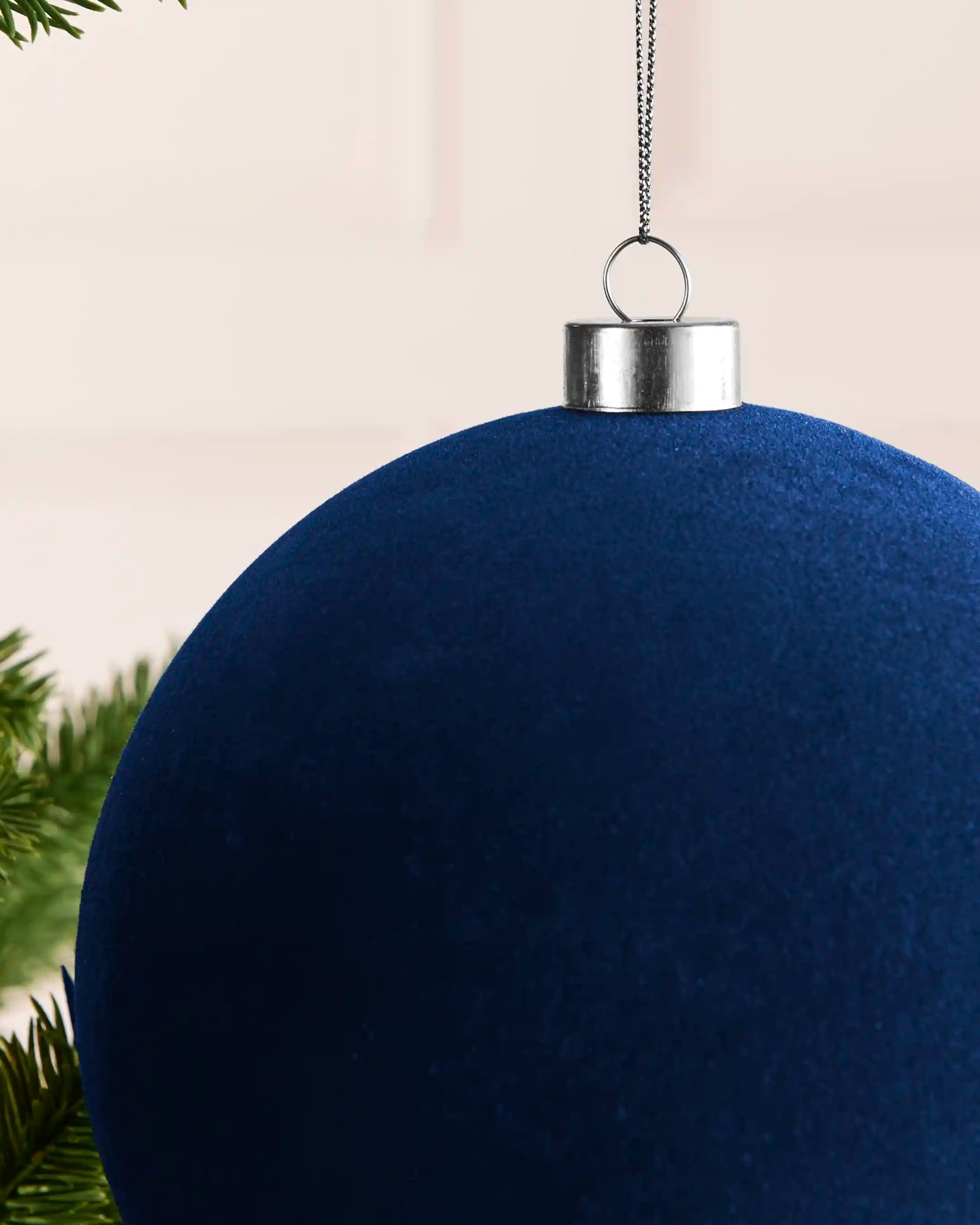 Close-up of a navy 15 cm oversized velvet traditional bauble showing the soft finish and silver cap.