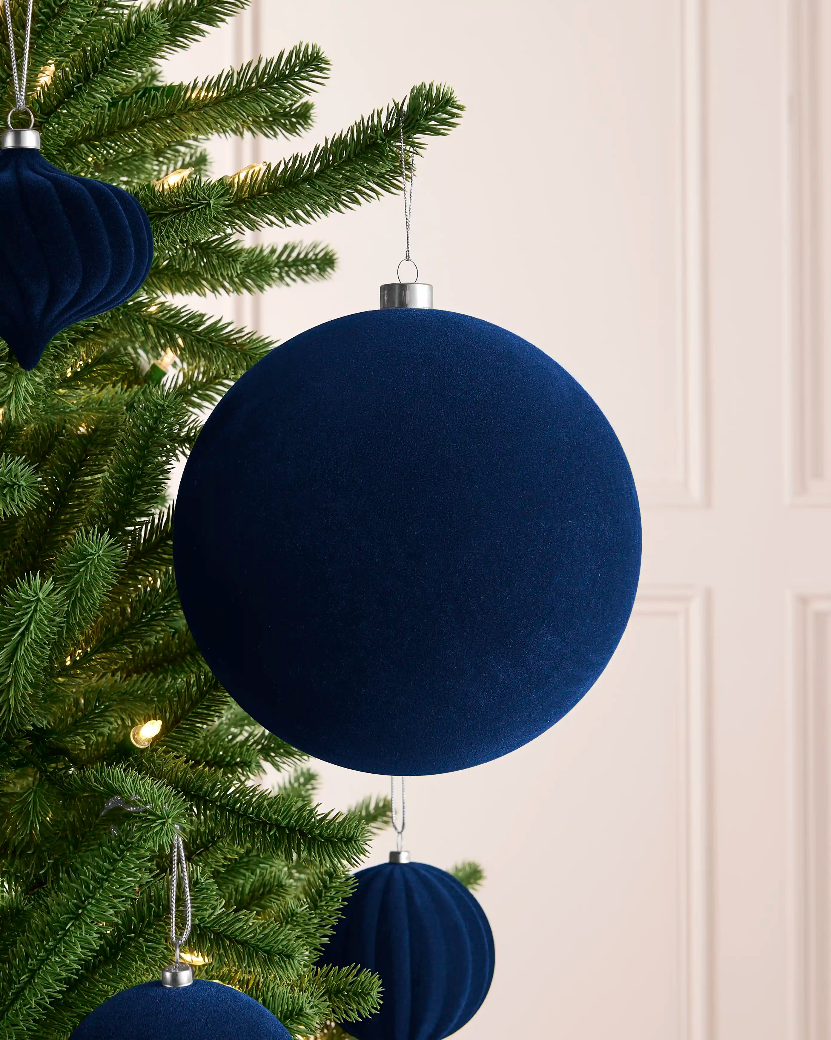 Navy 20 cm oversized velvet traditional bauble displayed on a Christmas tree with coordinating navy ornaments.