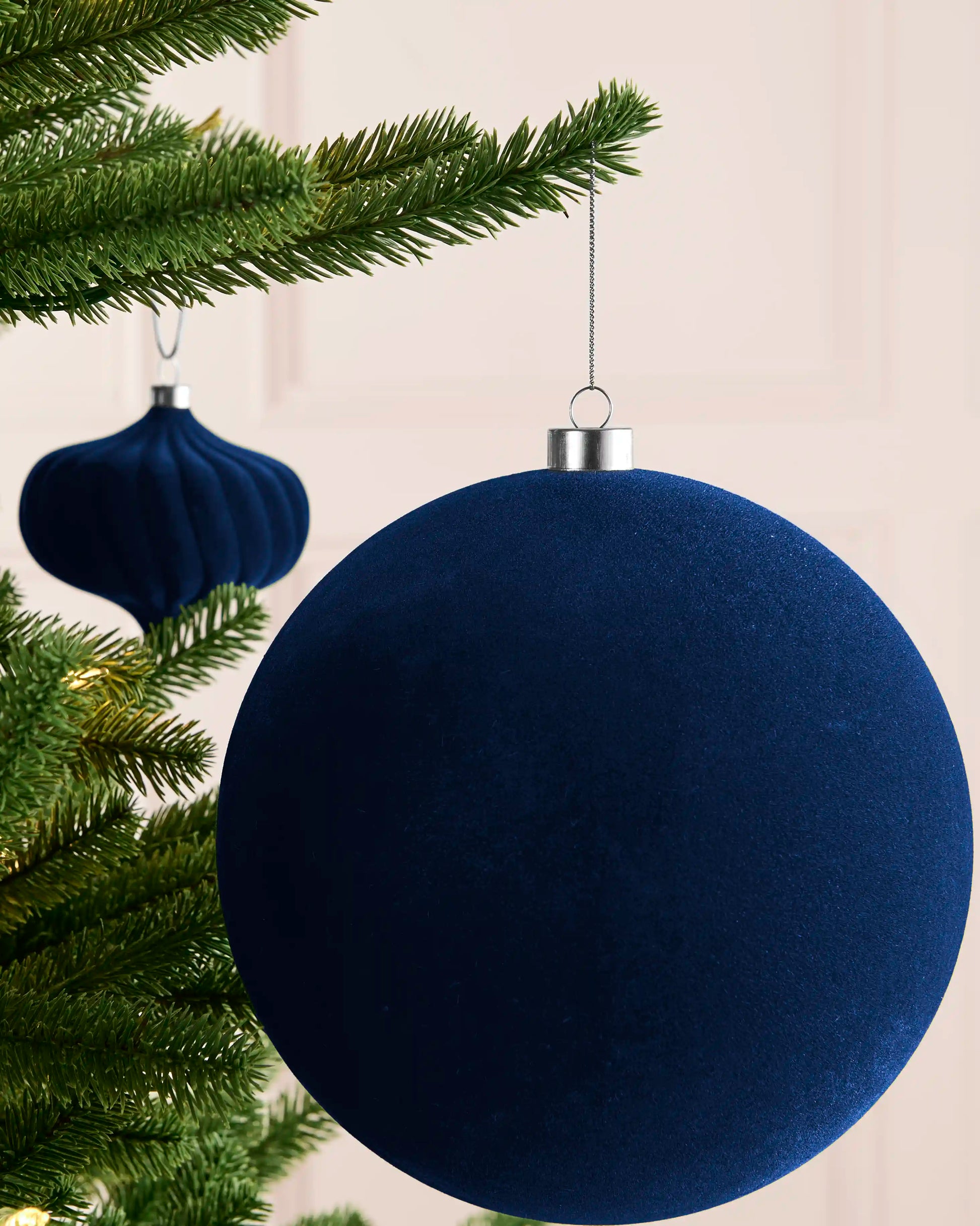 Large navy 20 cm oversized velvet traditional bauble styled on a Christmas tree with matching navy baubles.