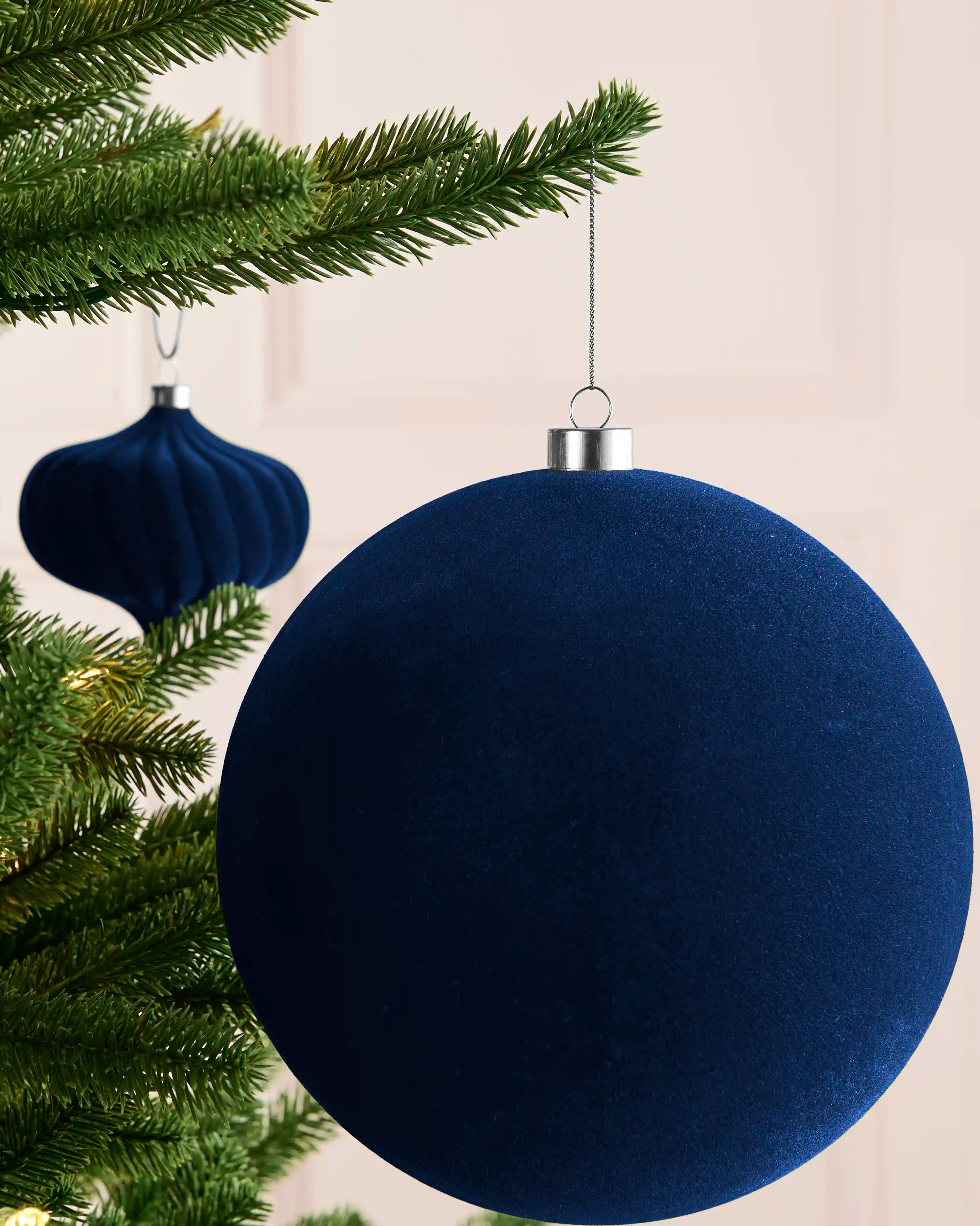 Large navy 20 cm oversized velvet traditional bauble styled on a Christmas tree with matching navy baubles.