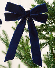 Navy 16.5 cm velvet double bow with long tails attached to a Christmas tree branch.