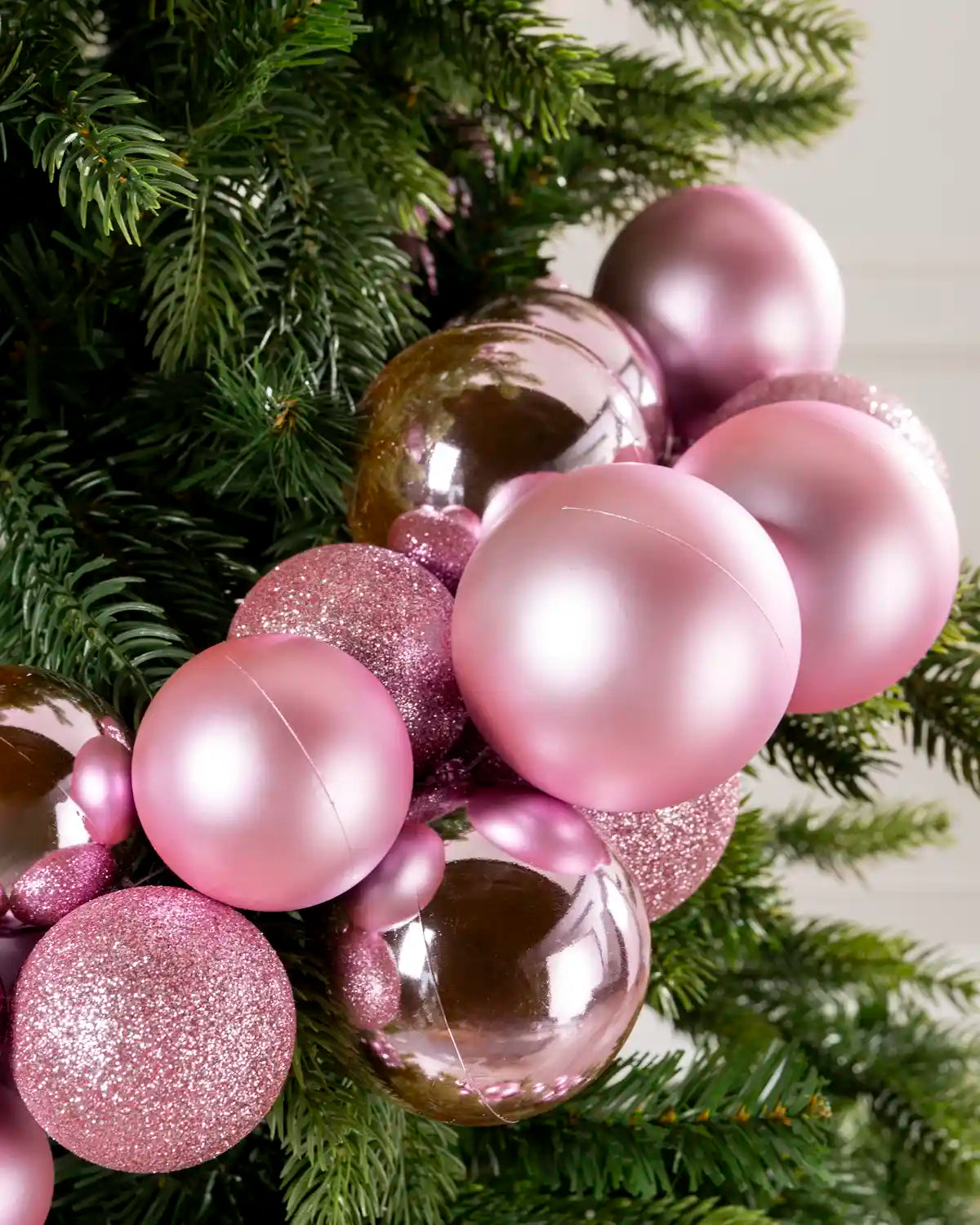 Close-up of pink baubles showing shiny, matt and glitter finishes on a Christmas tree.