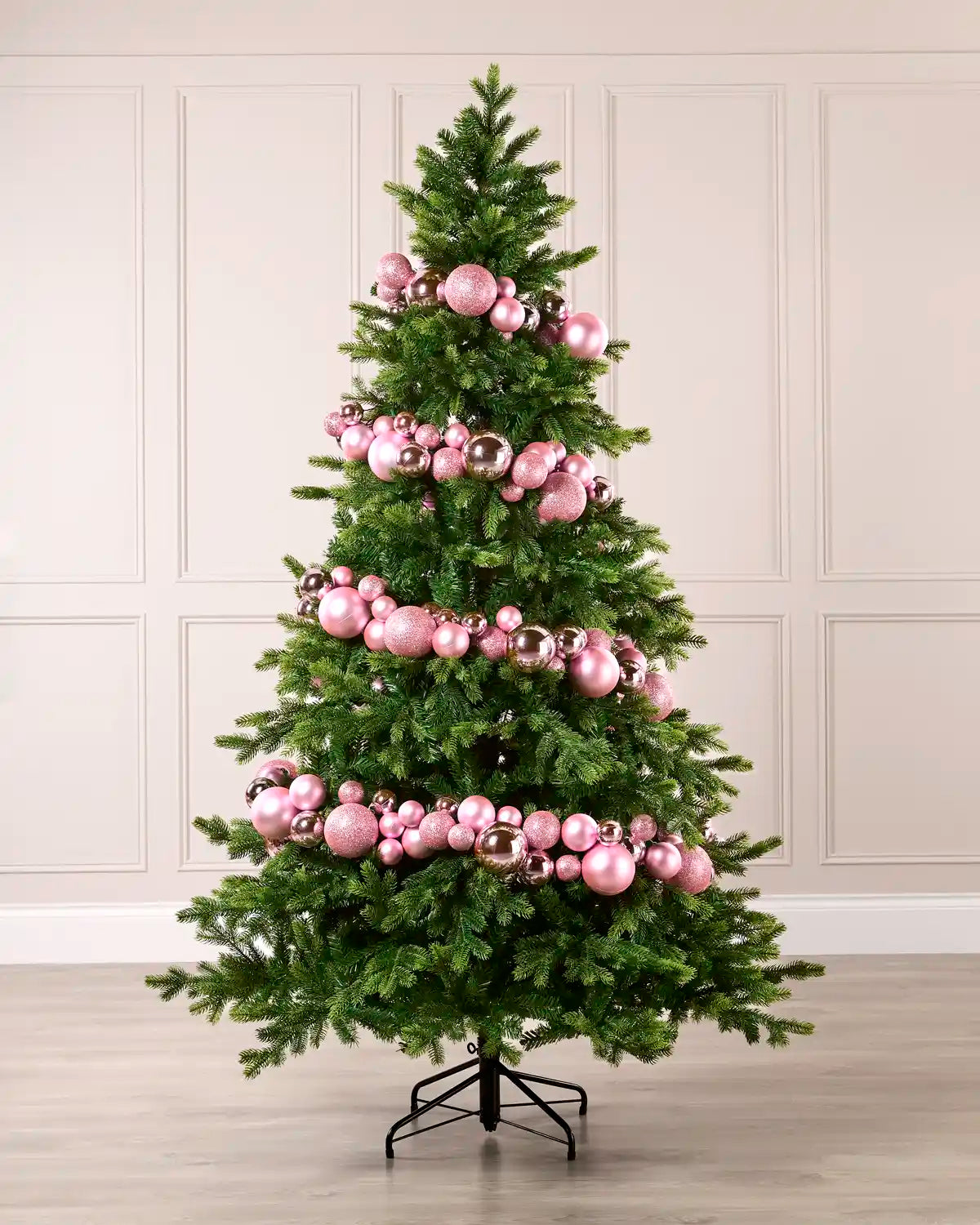 Pink bauble garland wrapped around a green Christmas tree with shiny, matt and glitter baubles.