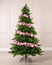 Pink bauble garland wrapped around a green Christmas tree with shiny, matt and glitter baubles.