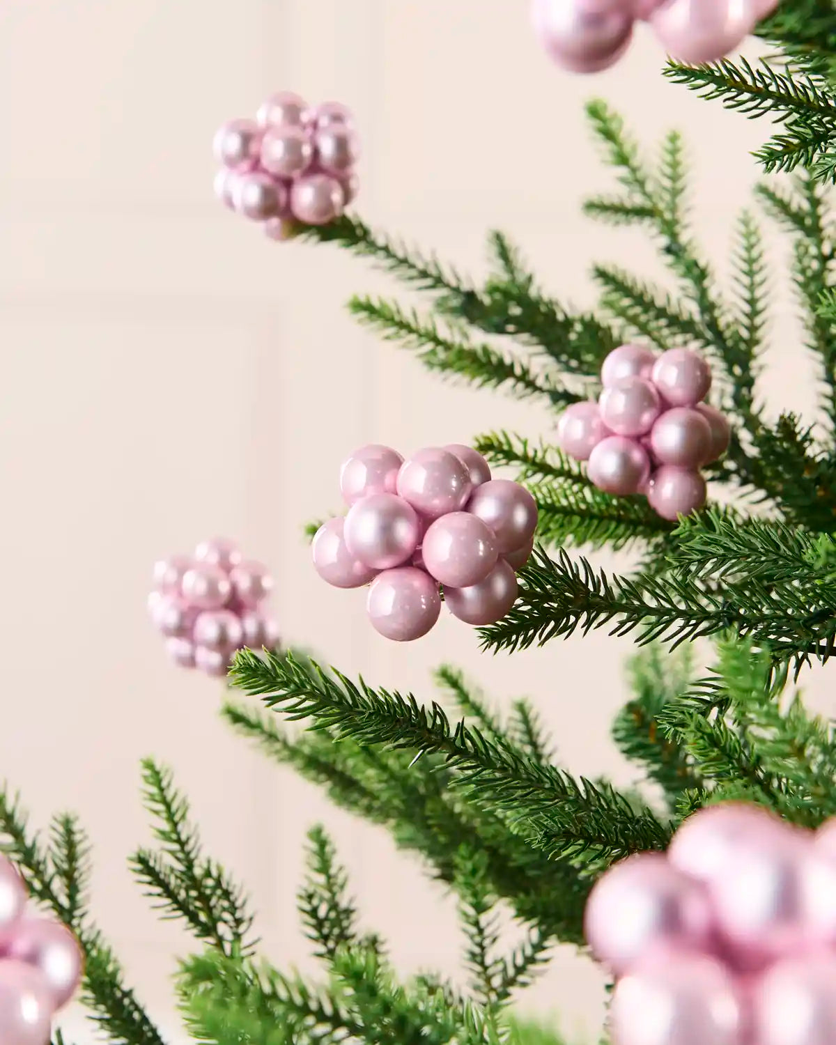 Pink glass berry cluster baubles arranged throughout a green Christmas tree.