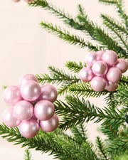 Close-up of pink glass berry cluster baubles with shiny and matt finishes on a Christmas tree.