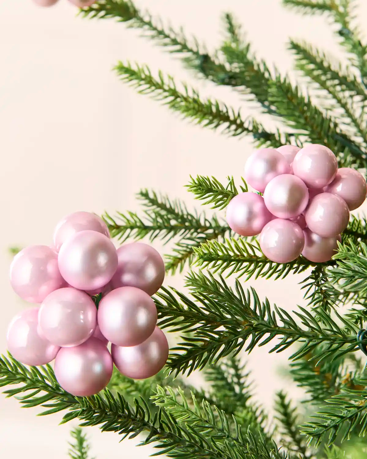 Close-up of pink glass berry cluster baubles with shiny and matt finishes on a Christmas tree.