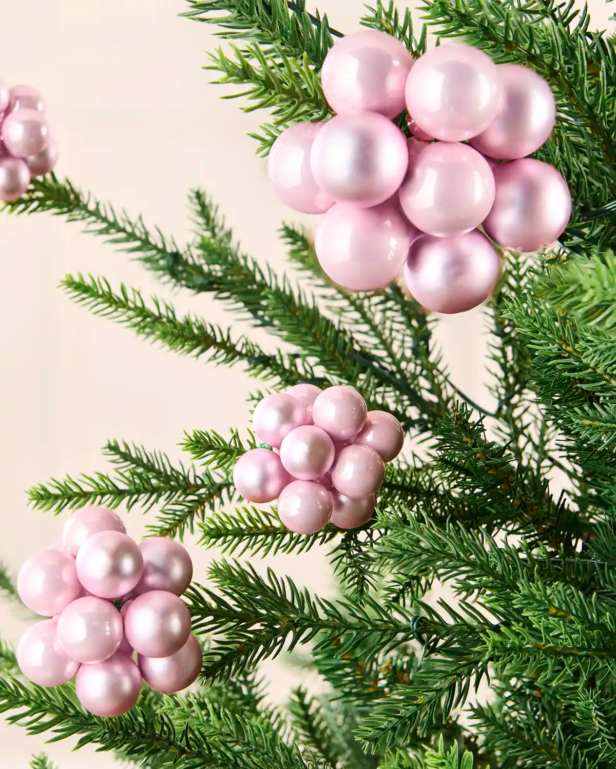 Pink berry cluster baubles with mixed shiny and matt glass finishes displayed on Christmas branches.