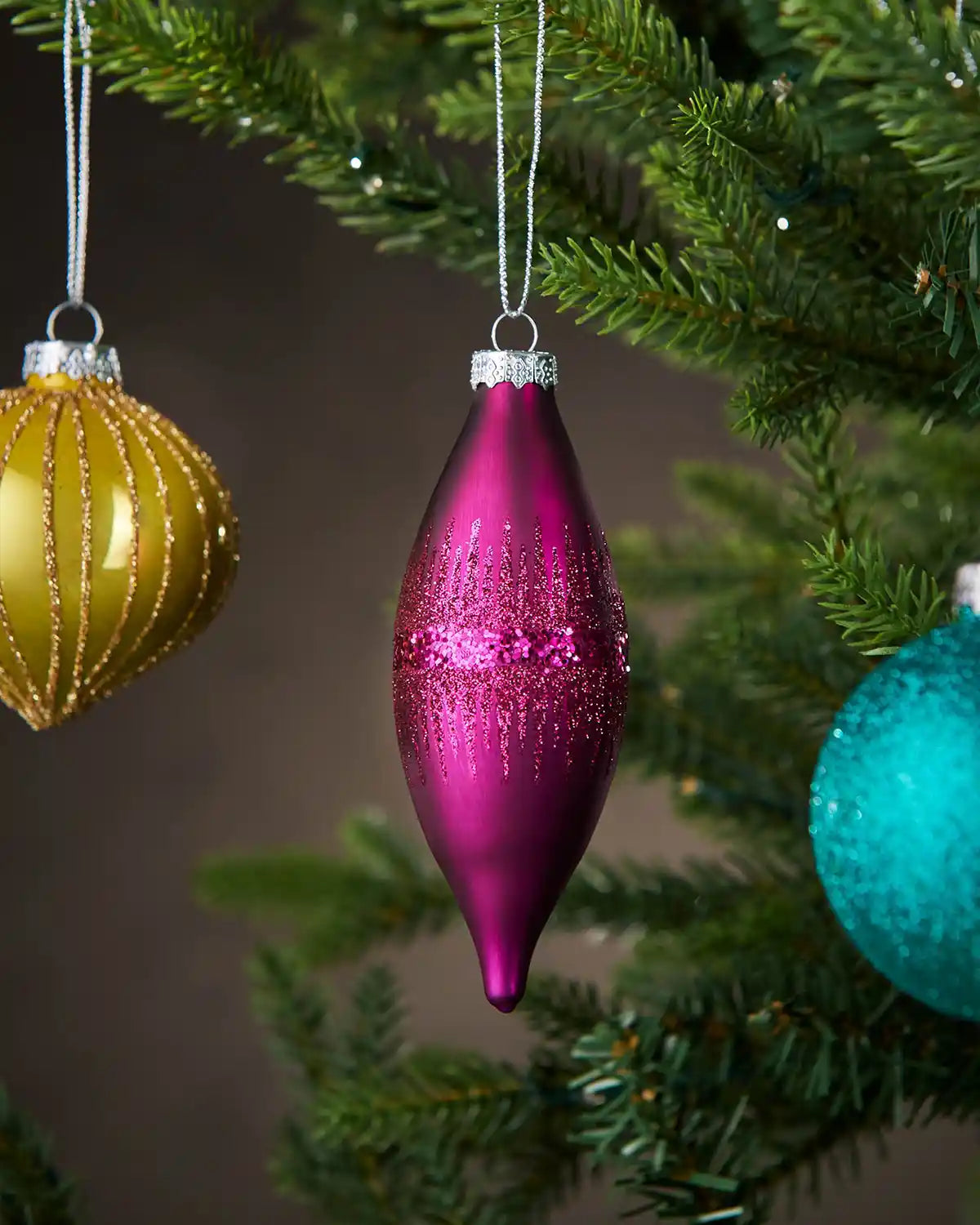 Pink glass teardrop bauble with glitter detail hanging on Christmas tree