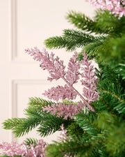 Pink glitter leaf pick arranged amongst green Christmas tree branches.