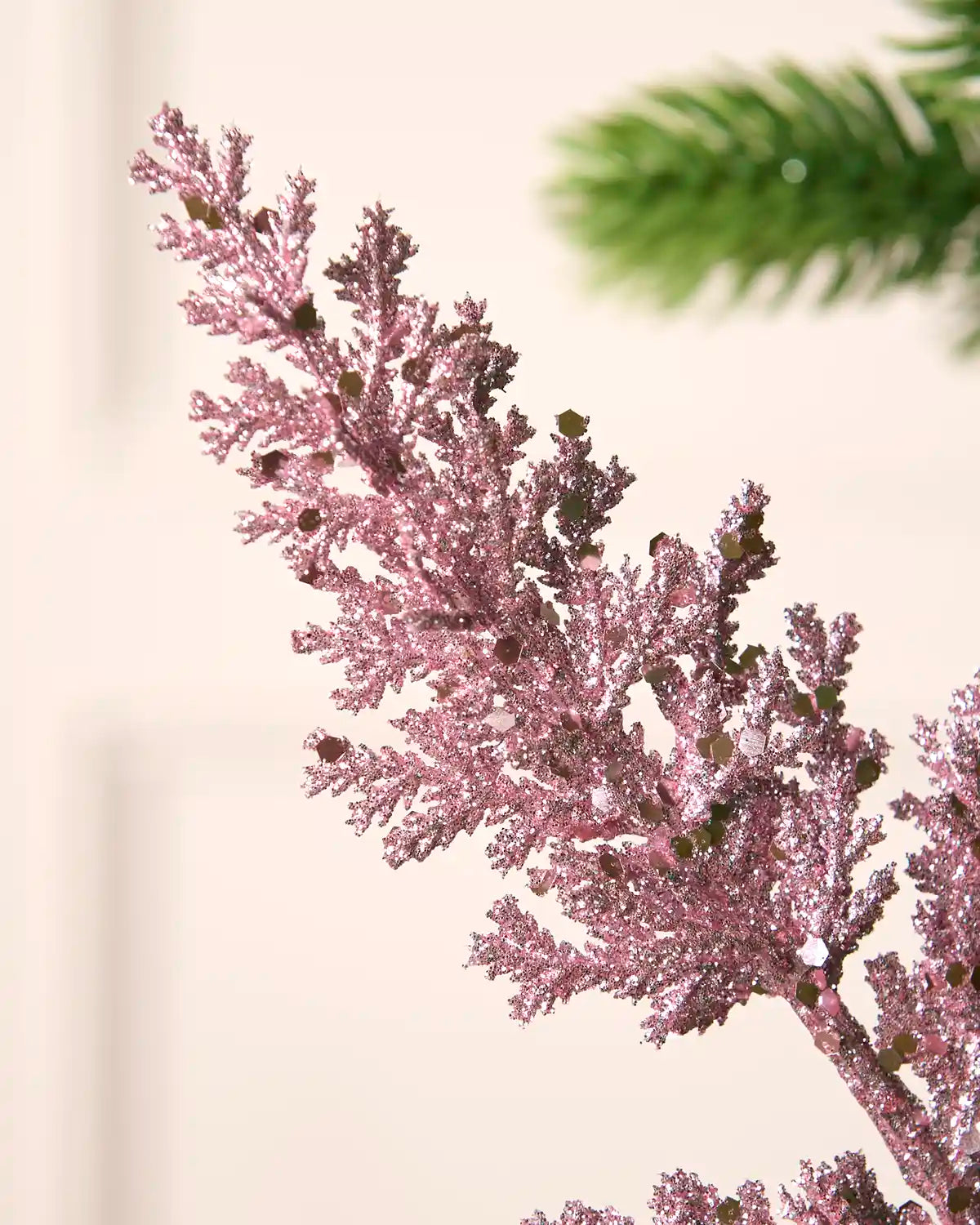 Close-up of pink glitter leaf foliage with scattered sequins creating a sparkling textured finish.