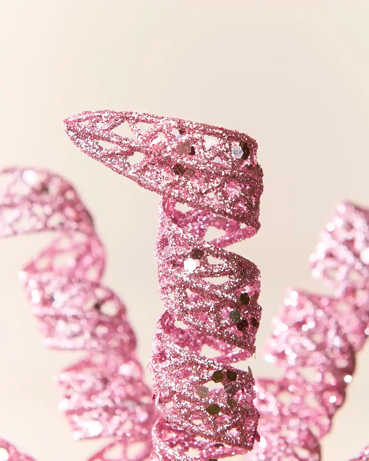 Detailed view of a pink glitter spiral pick showing its curled shape and textured reflective finish.