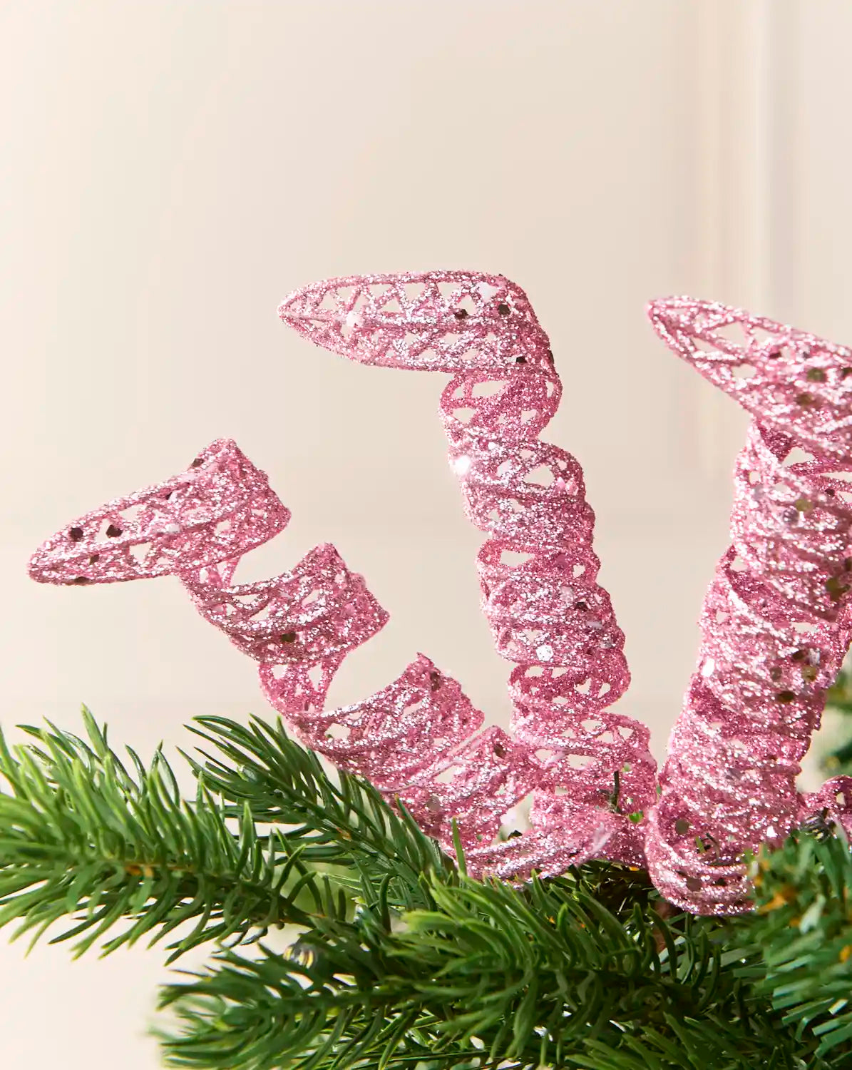 Close-up of pink glitter spiral picks showing curled openwork shapes and reflective sequin details.