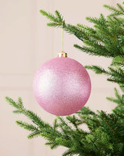 Pink 15 cm oversized shatterproof bauble with a glitter finish, gold cap and hanging string displayed on a Christmas tree.