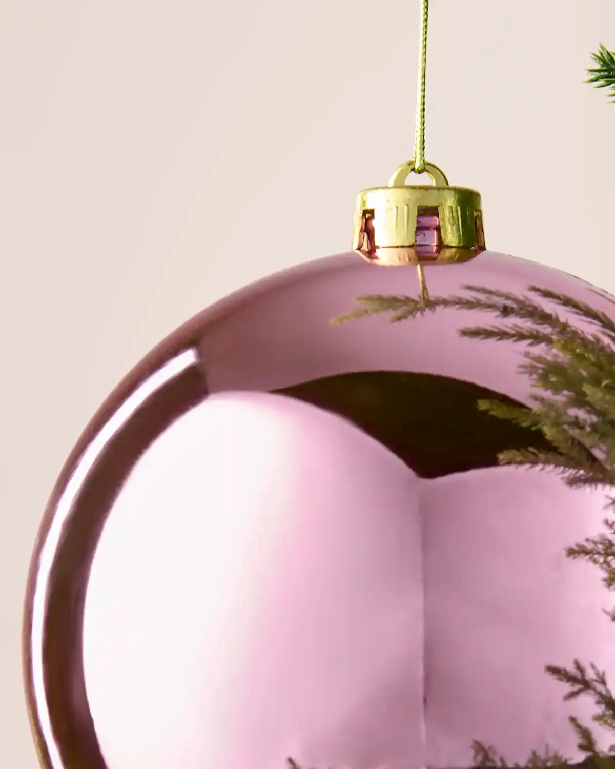 Detailed close-up of the shiny pink shatterproof bauble with gold cap and hanging string.