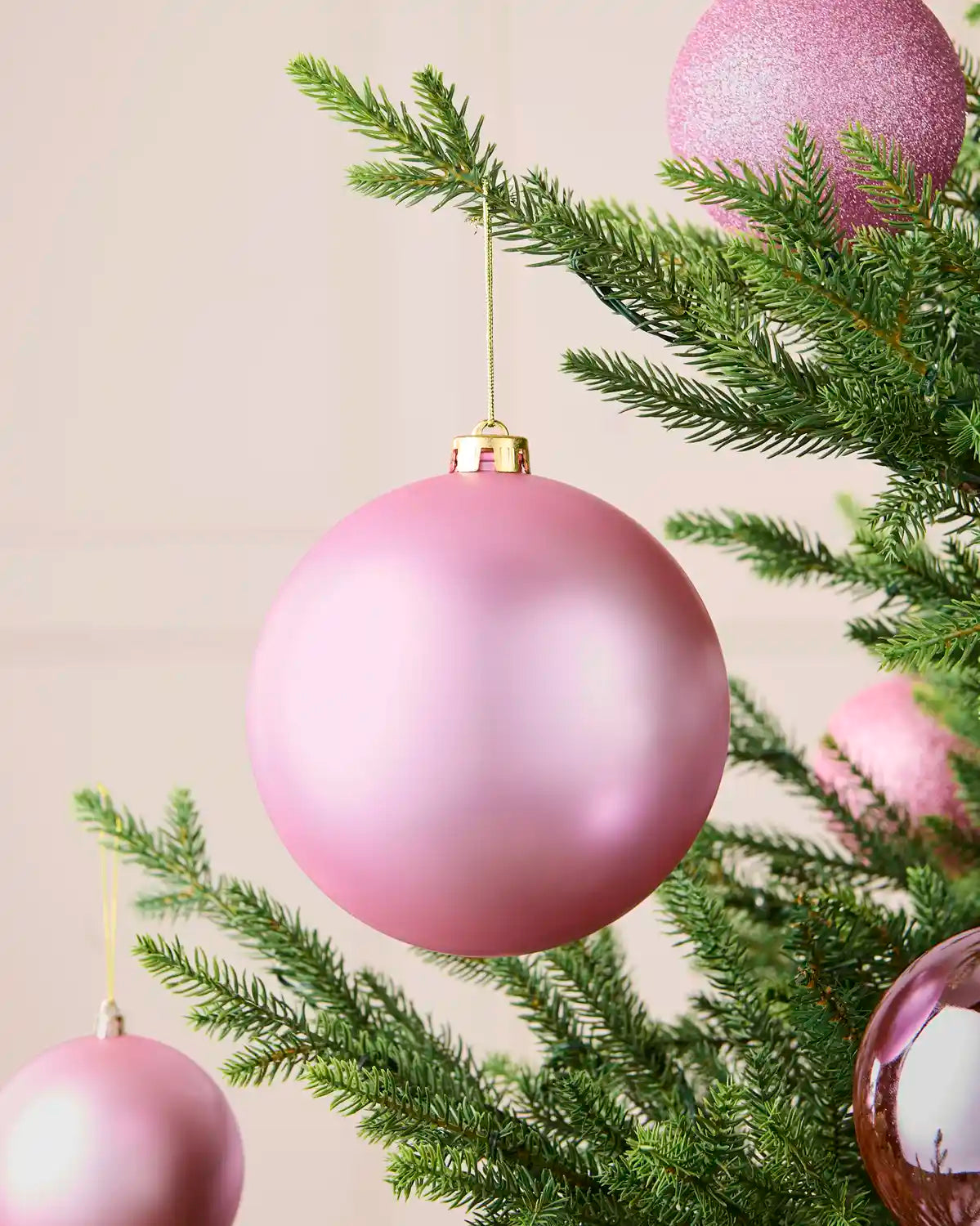 Matt pink 15 cm shatterproof bauble displayed on a Christmas tree with coordinating shiny and glitter baubles.