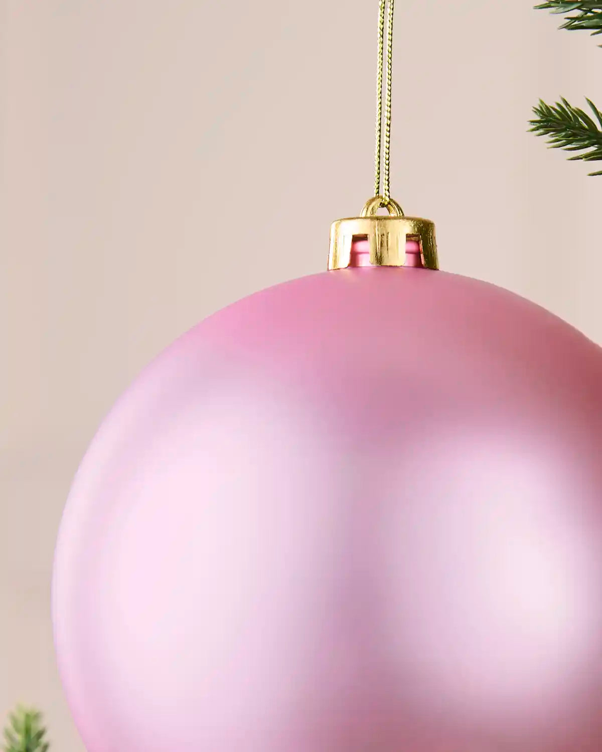 Detailed close-up of the matt pink shatterproof bauble with its gold cap and matching hanging string.