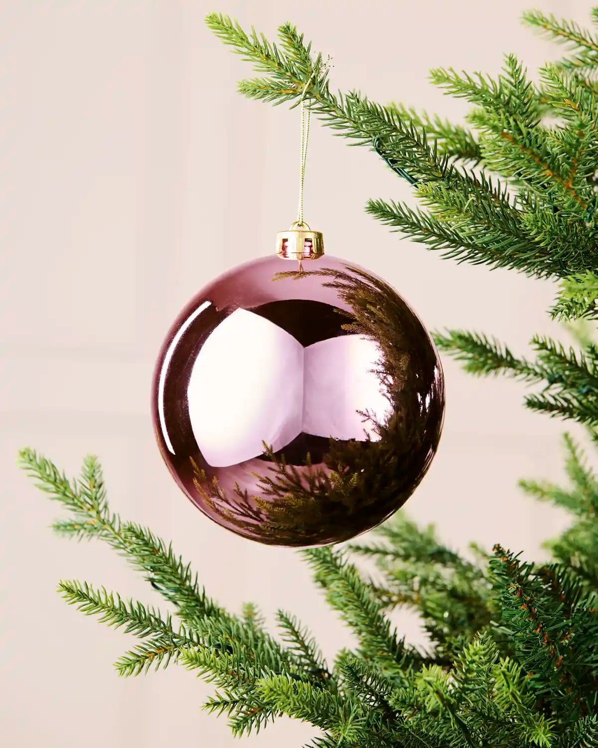 Shiny pink oversized shatterproof bauble measuring 15 cm, hanging from an artificial Christmas tree with a gold cap and string.