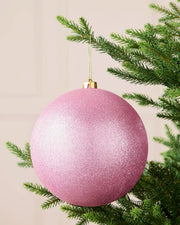 Pink 20 cm oversized shatterproof bauble with a glitter finish, gold cap and hanging string displayed on a Christmas tree.