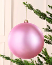 Pink 20 cm oversized shatterproof bauble with a smooth matt finish, gold cap and hanging string on a Christmas tree.