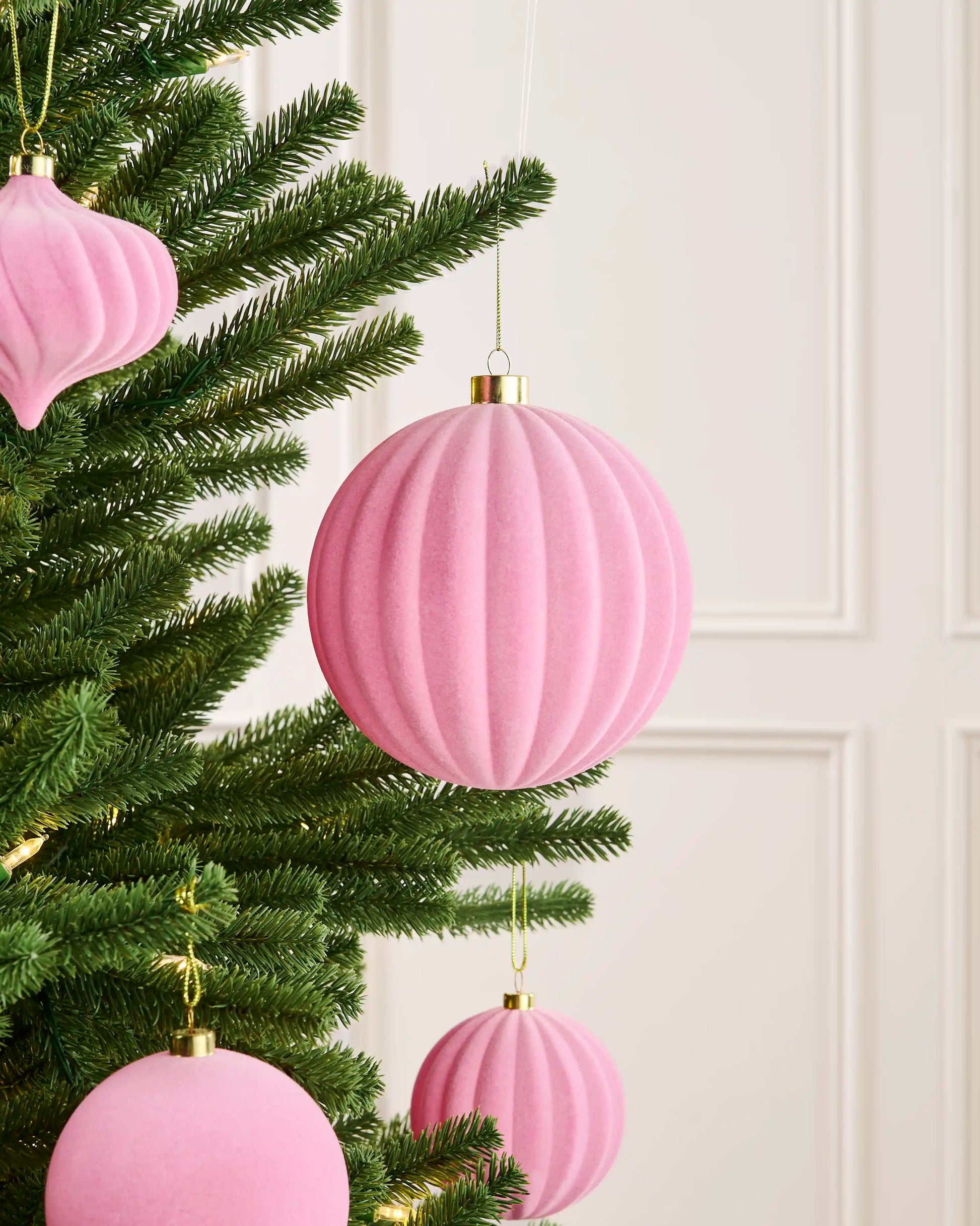 Pink 15 cm oversized ribbed velvet bauble displayed among matching pink decorations on a Christmas tree.