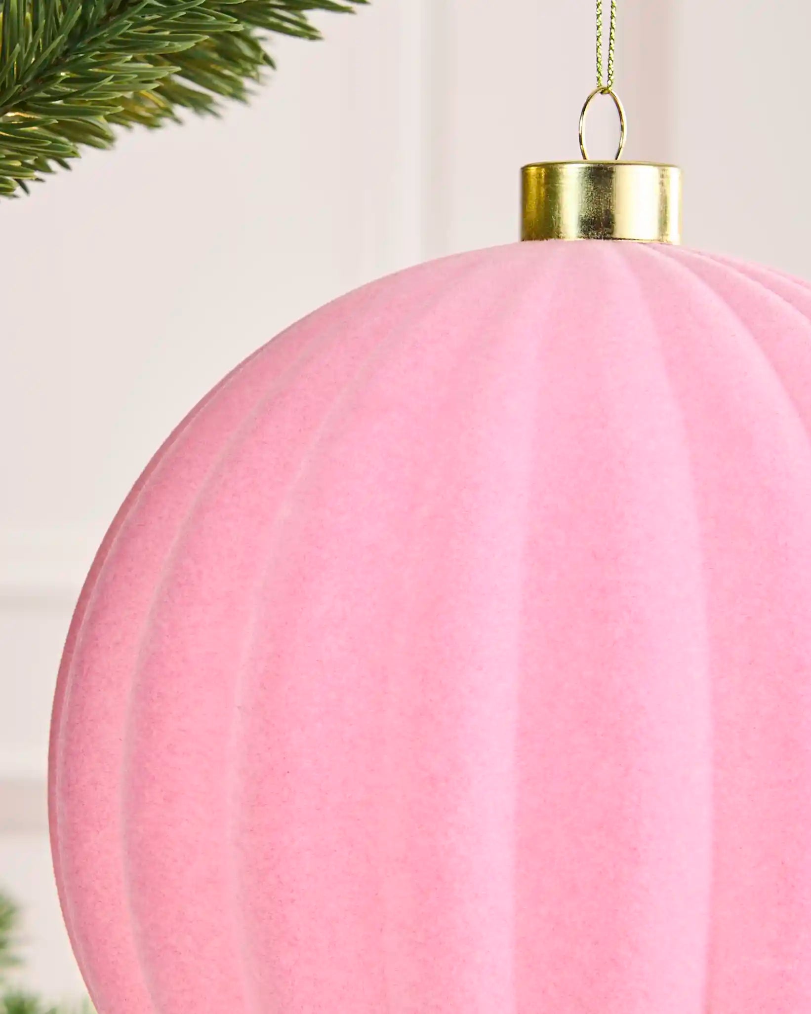 Close-up of the pink velvet ribbed finish, gold metal cap and hanging string on the 15 cm bauble.