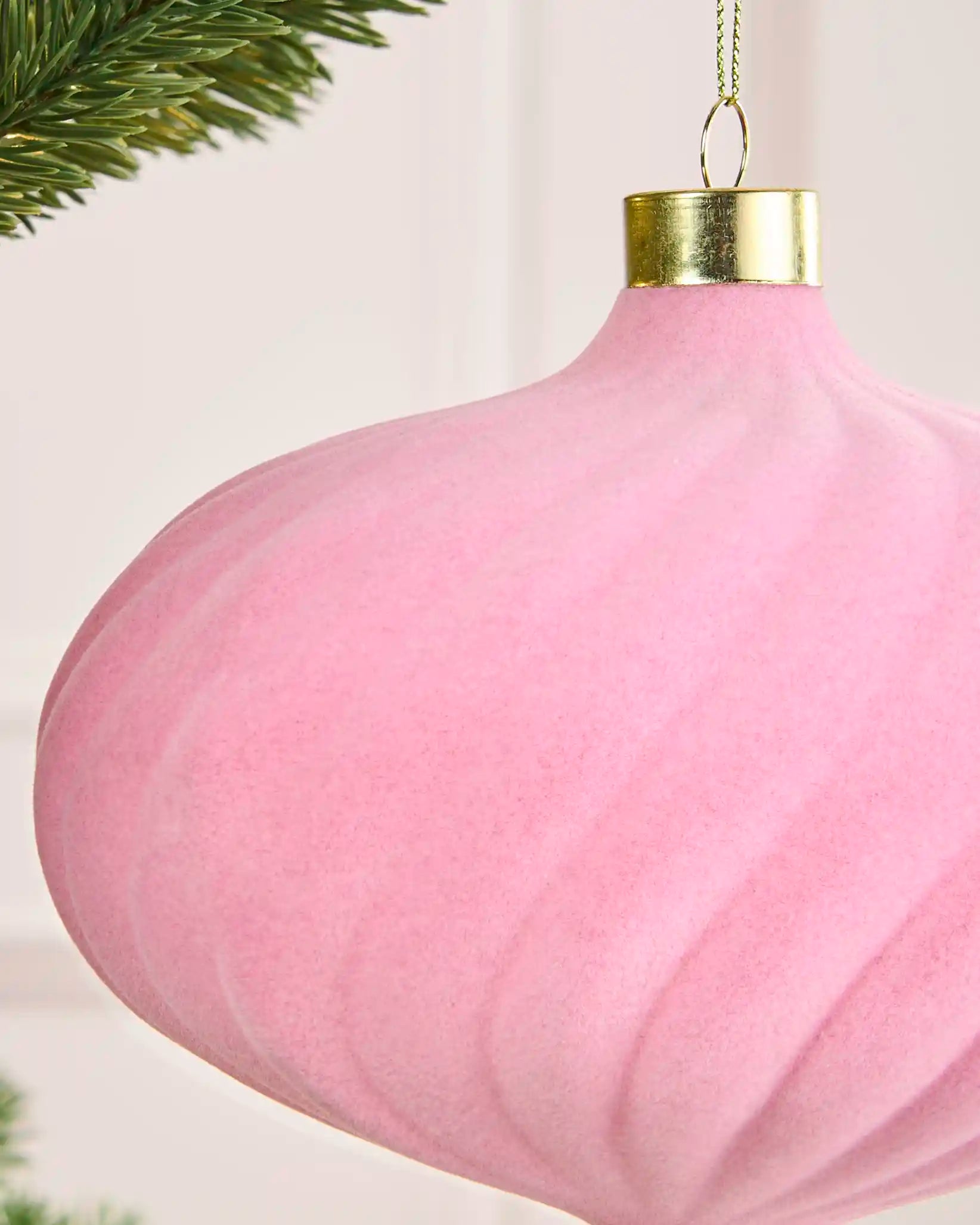Close-up of a pink 15 cm oversized velvet spiral bauble showing its soft texture, raised spiral detail and gold cap.