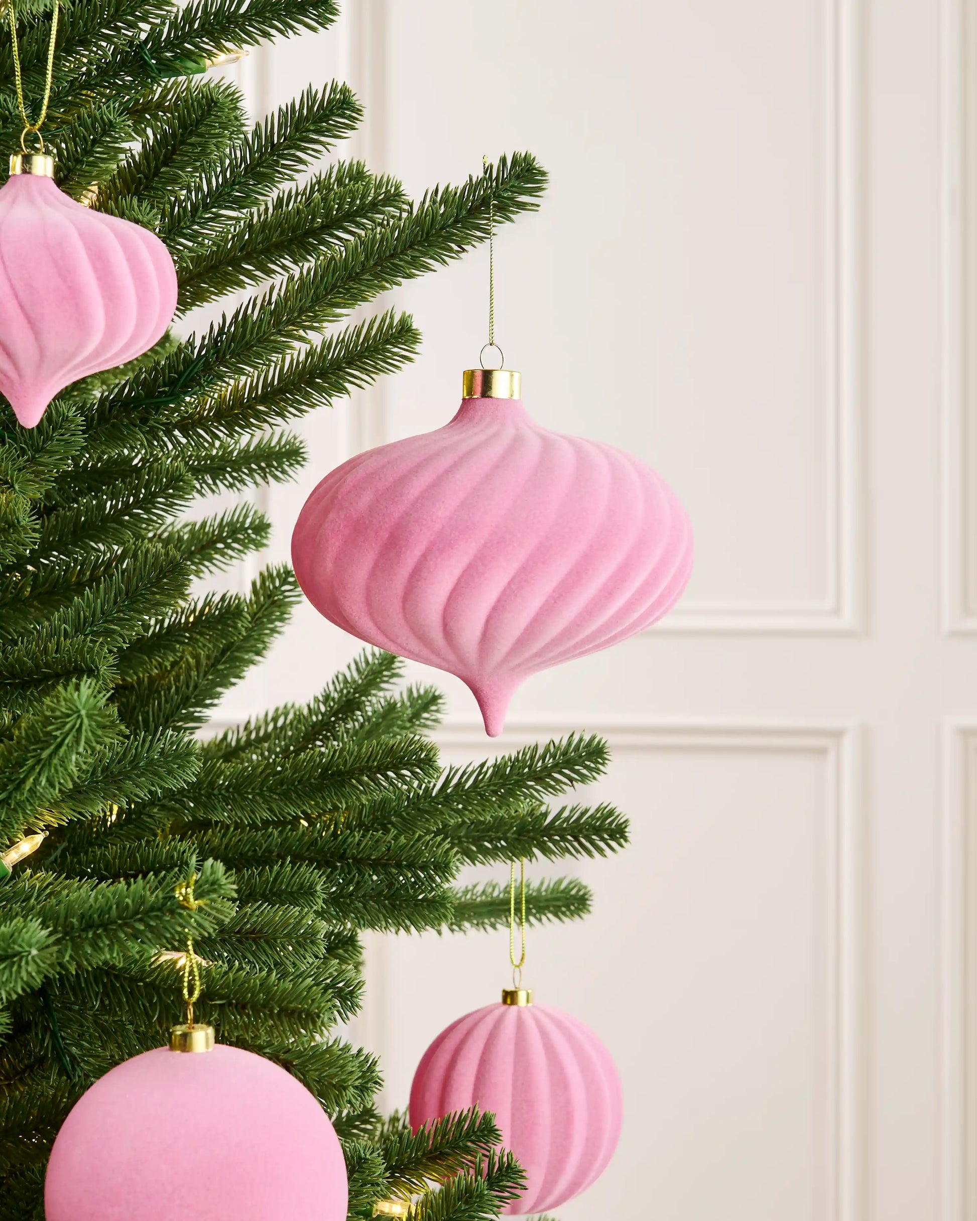 Pink 15 cm oversized velvet spiral bauble styled on a Christmas tree with coordinating pink baubles.