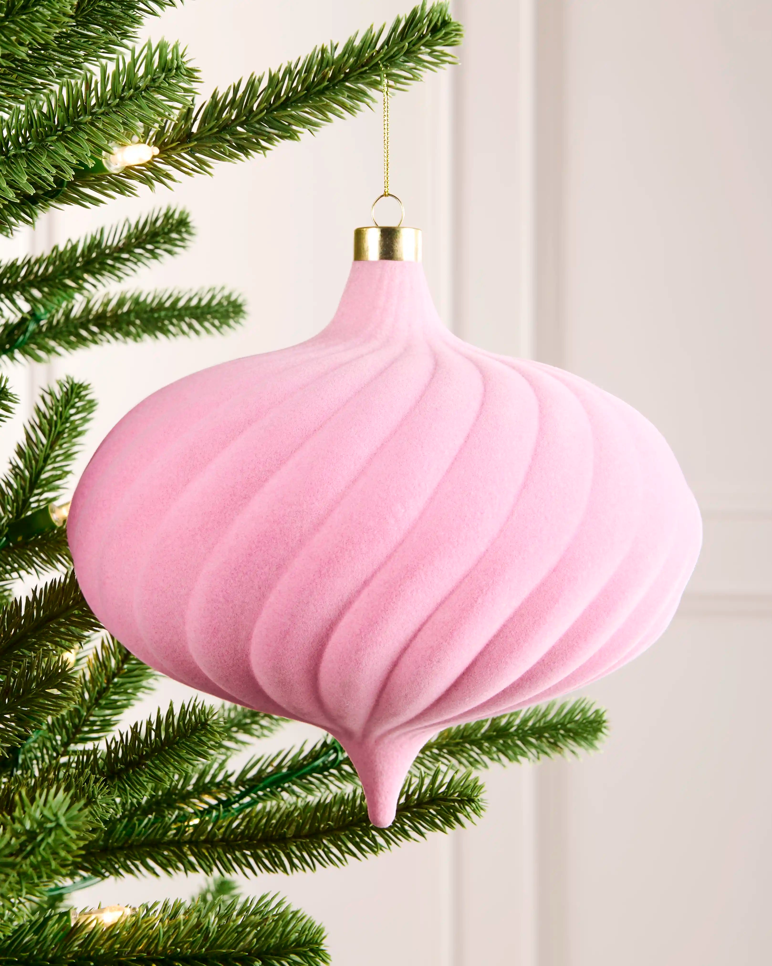 20 cm pink oversized velvet spiral bauble hanging on a Christmas tree with a gold cap and gold hanging string.