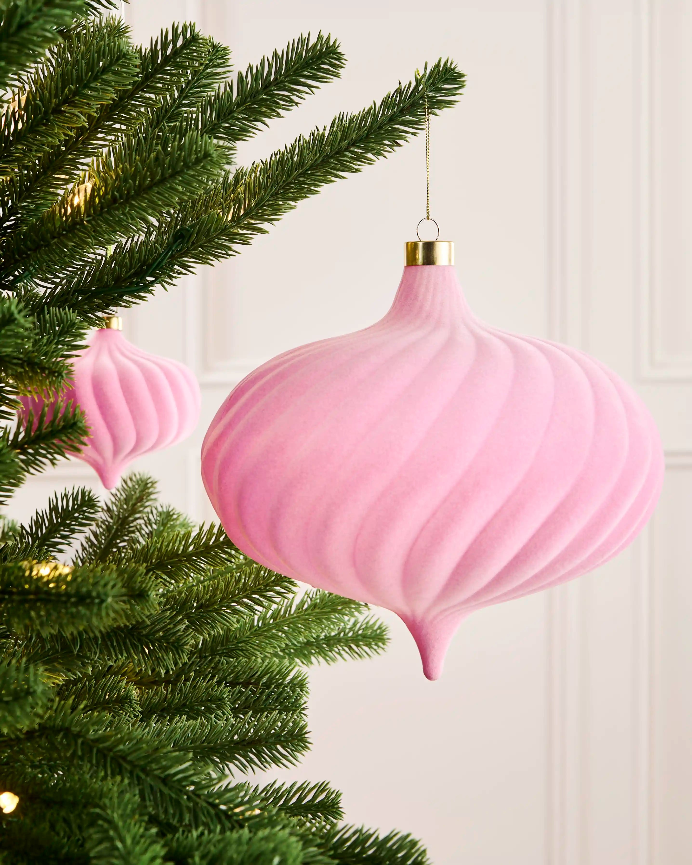 Pink 20 cm oversized velvet spiral bauble displayed on a Christmas tree with a matching pink bauble in the background.