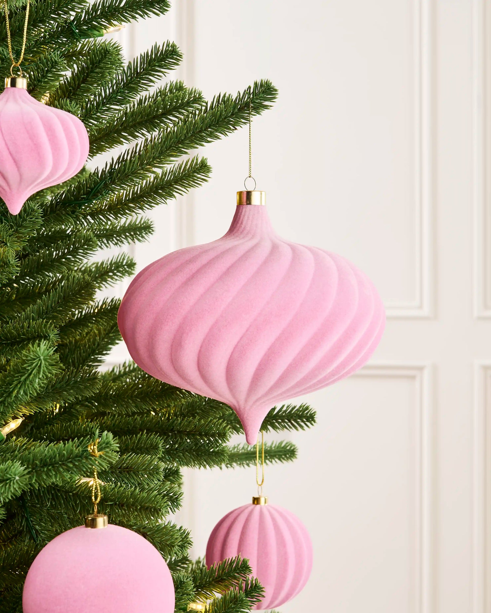 Large pink 20 cm oversized velvet spiral bauble styled on a Christmas tree with coordinating pink ornaments.