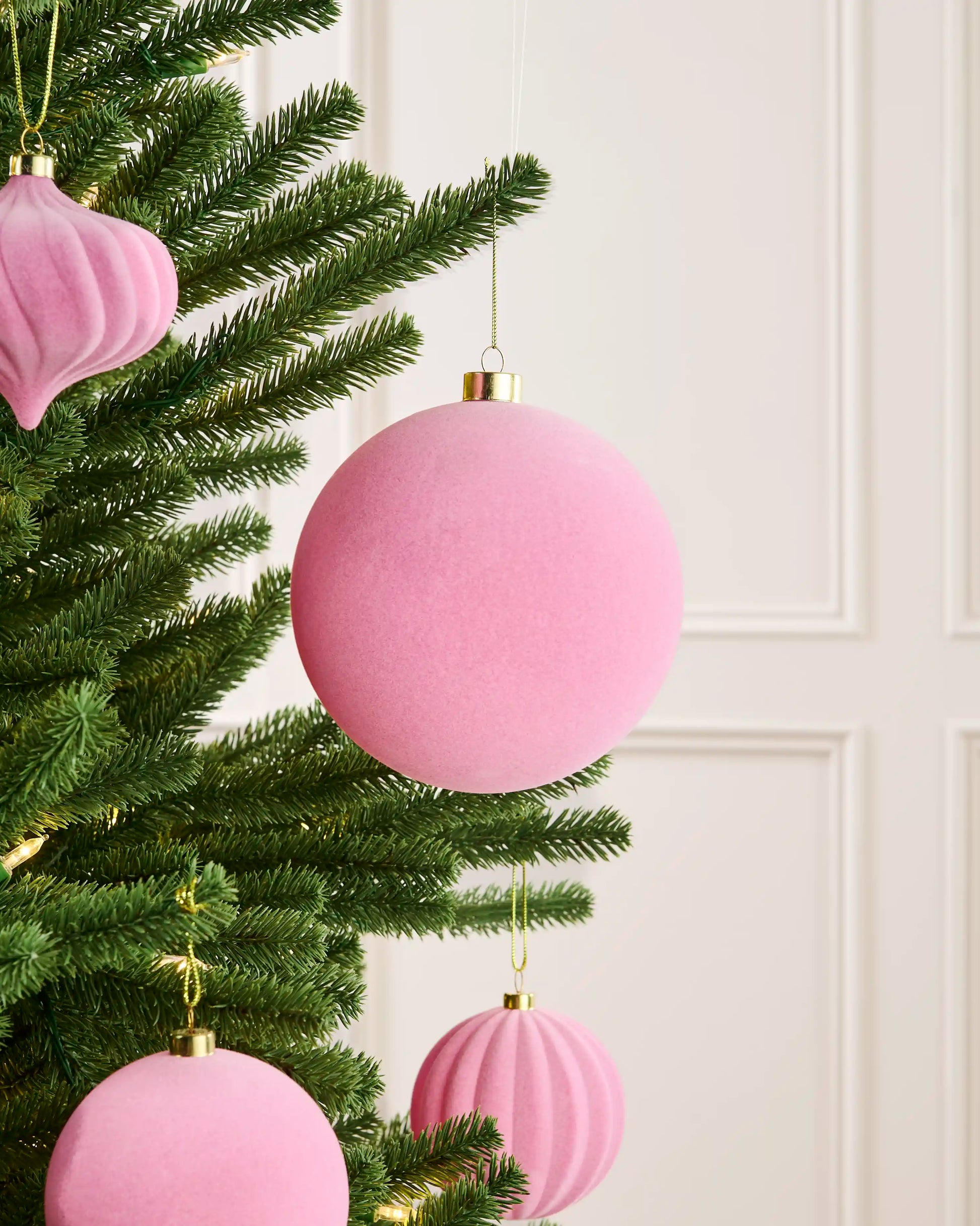 Pink 15 cm oversized velvet bauble displayed among matching pink decorations on a Christmas tree.