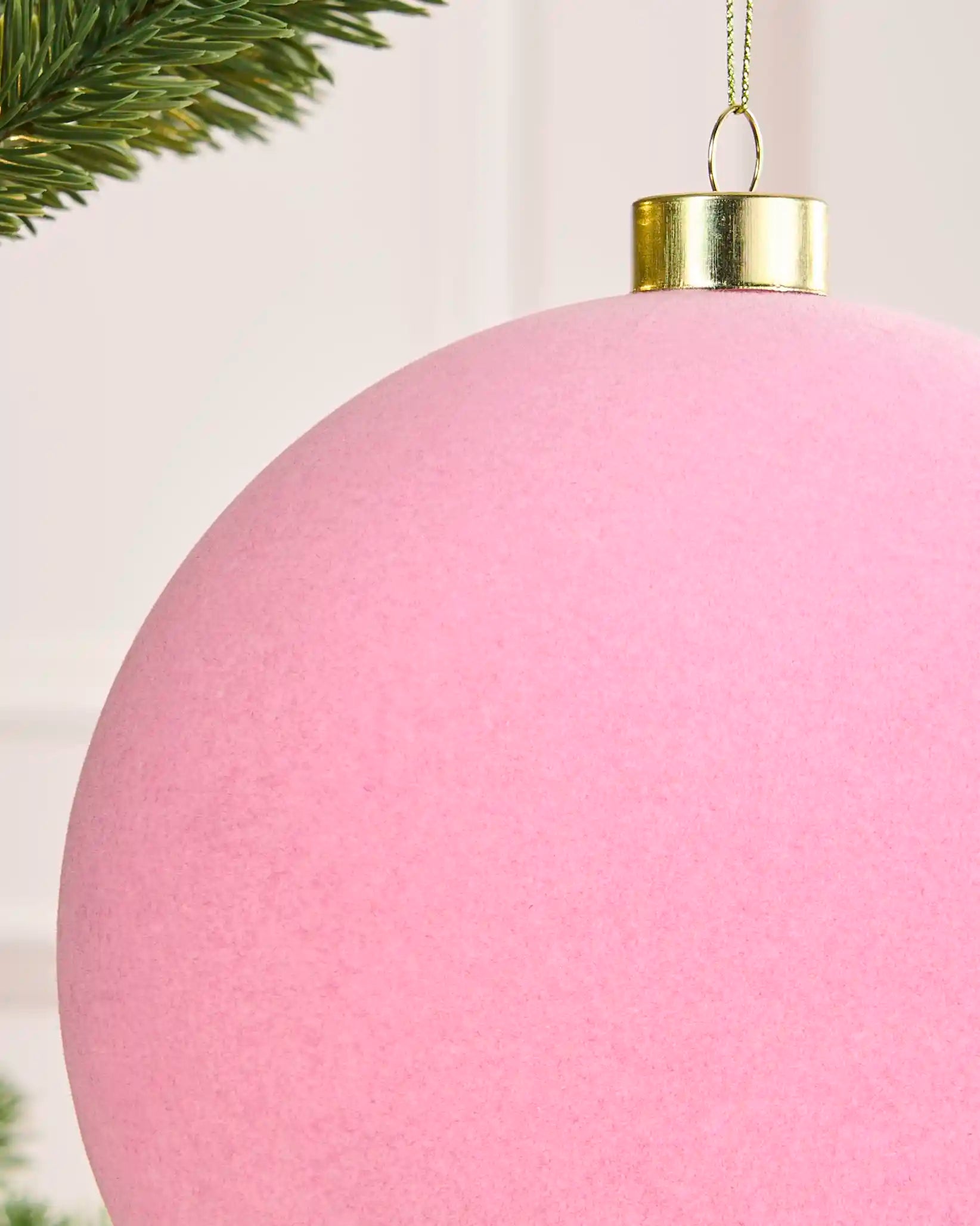 Close-up of the soft pink velvet finish, gold metal cap and hanging string on the 15 cm bauble.