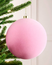 20 cm pink oversized velvet traditional bauble hanging on a Christmas tree with a gold cap and hanging string.