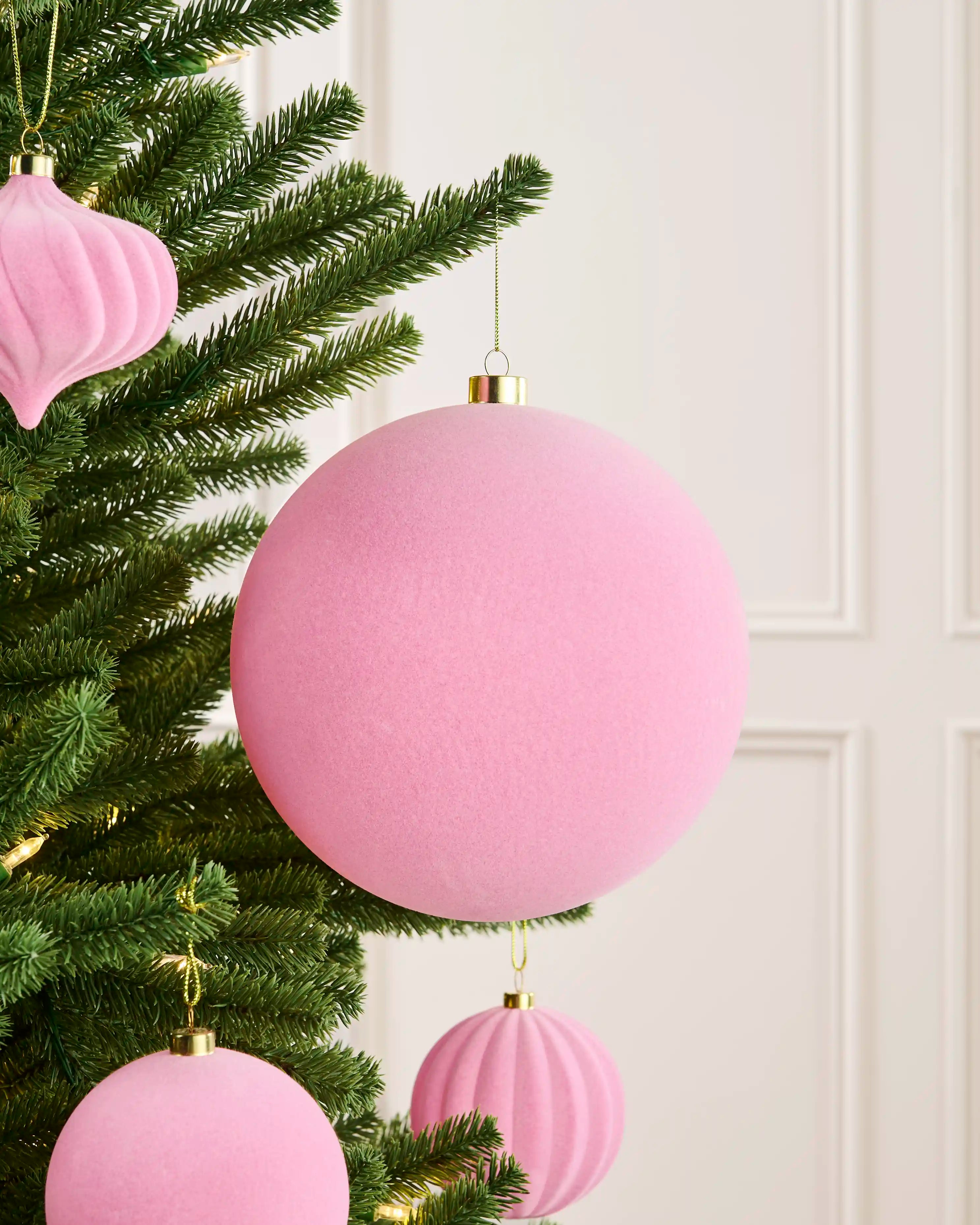 Large pink 20 cm oversized velvet traditional bauble styled on a Christmas tree with coordinating pink ornaments.