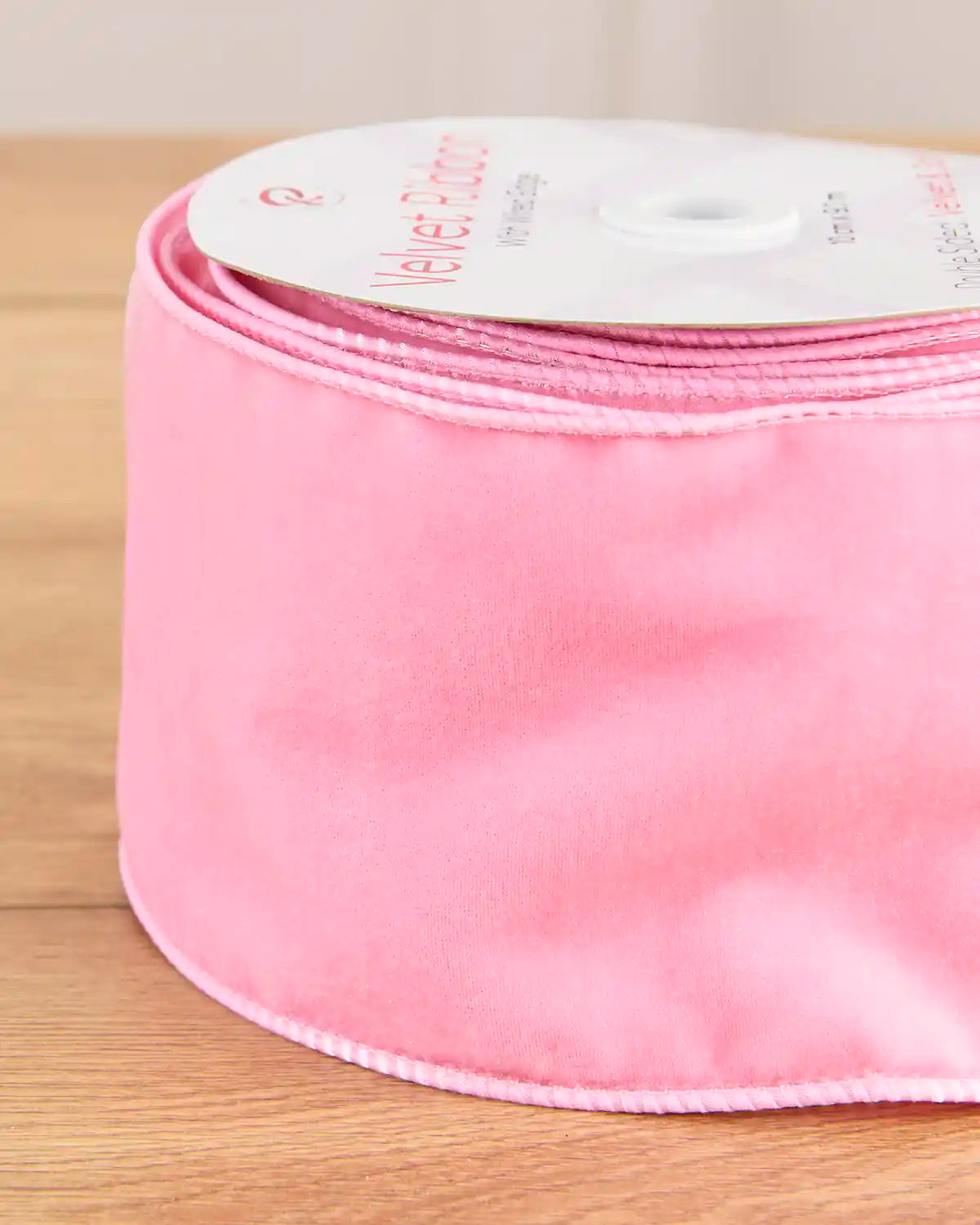 Close-up of 10 cm wide pink velvet ribbon showing its soft surface and wired edges.