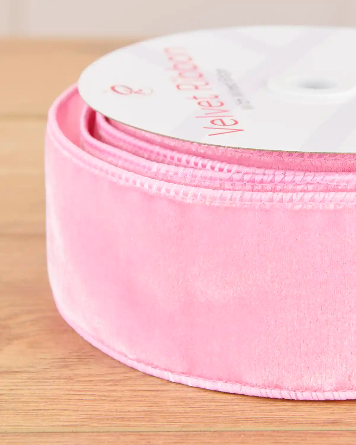 Close-up of 6  cm wide pink velvet ribbon showing its soft surface and wired edges.
