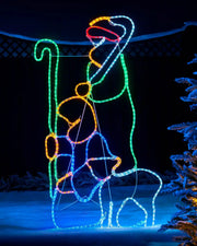 Pre-lit 2 shepherds with sheep silhouette rope light displayed outdoors at night